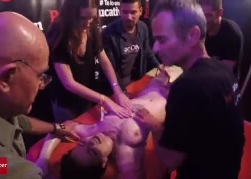 A group of people massage this young and tattoed girl at the same time in public